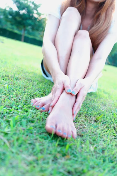 Asiatique détendue jeune femme avec pieds nus assis sur l'herbe — Photo