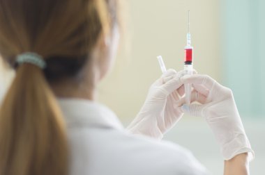 Elinde kırmızı aşı şırınga ile doktor