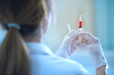 Elinde kırmızı aşı şırınga ile doktor