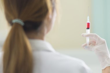 Elinde kırmızı aşı şırınga ile doktor