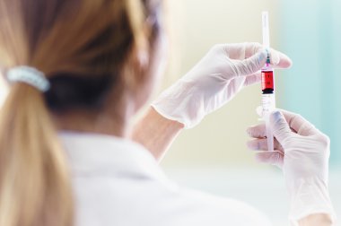 Elinde kırmızı aşı şırınga ile doktor