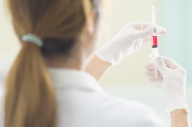 Elinde kırmızı aşı şırınga ile doktor