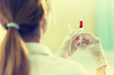 Elinde kırmızı aşı şırınga ile doktor
