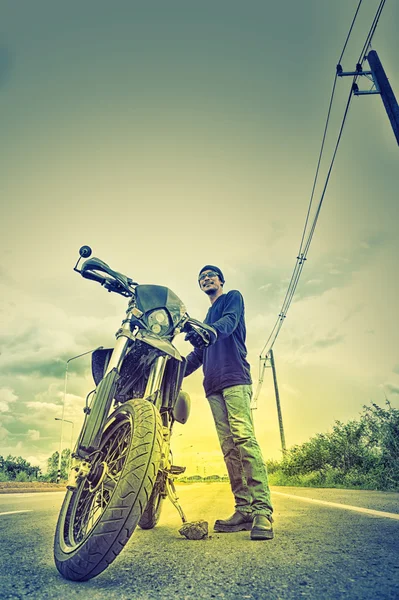 Портрет человека-байкера, стоящего на дороге с мотоциклом — стоковое фото