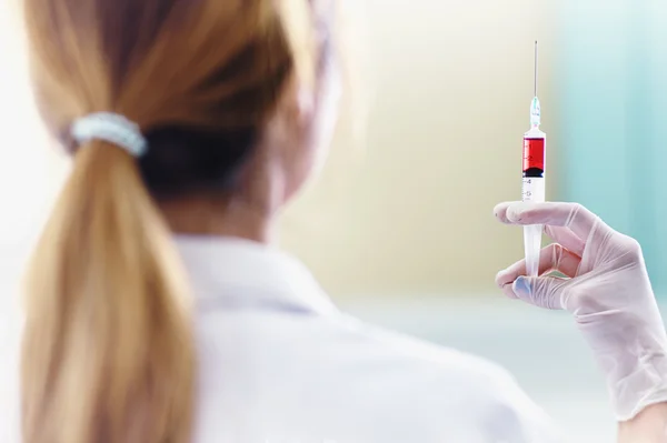 Médico con jeringa de vacuna roja en la mano —  Fotos de Stock