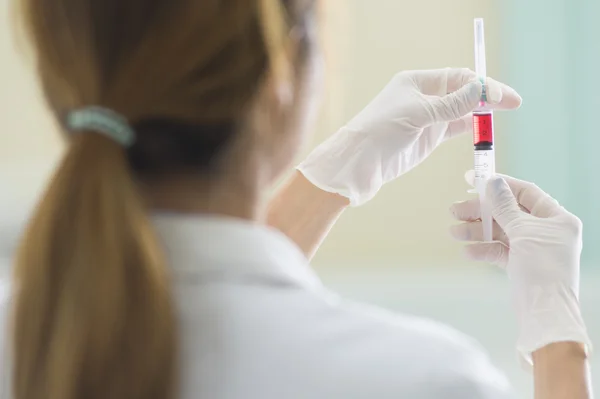 Médico con jeringa de vacuna roja en la mano —  Fotos de Stock