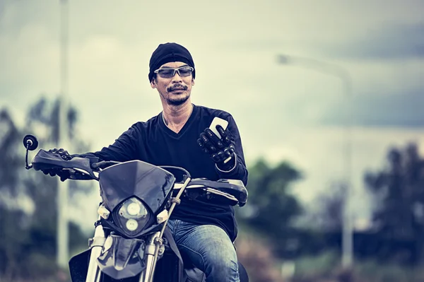 Asia guapo hombre motorista celebración de teléfono en la motocicleta — Foto de Stock