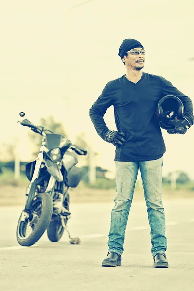 Портрет человека-байкера, стоящего на дороге с мотоциклом — стоковое фото