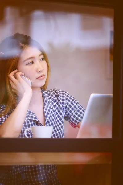 Mujer asiática hablando de teléfono en la cafetería y disfrutando del café — Foto de Stock