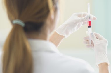 Elinde kırmızı aşı şırınga ile doktor