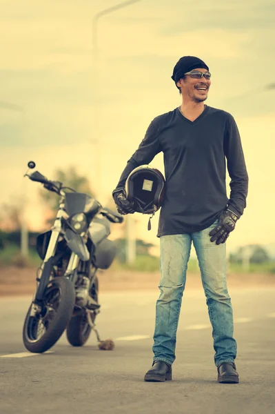 Portrait of man biker standing on road with motorcycle — Stock Photo, Image