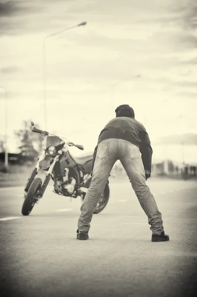 Motociclista relajarse con la moto en la puesta del sol . —  Fotos de Stock