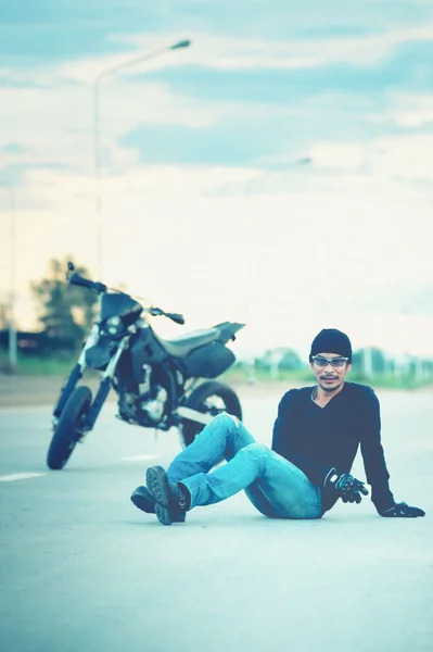 Biker relax sitting with motorbike on road in sunset