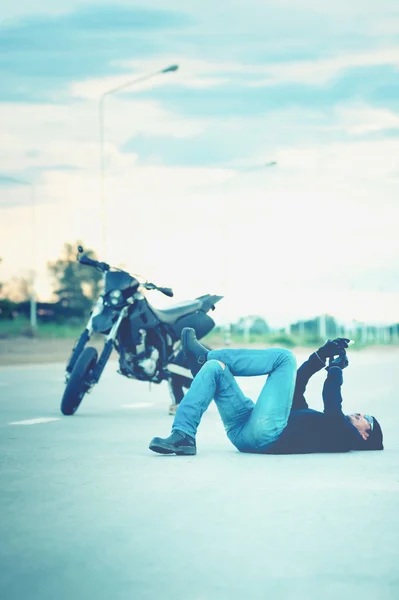 Biker relaxar deitado com moto na estrada ao pôr do sol — Fotografia de Stock