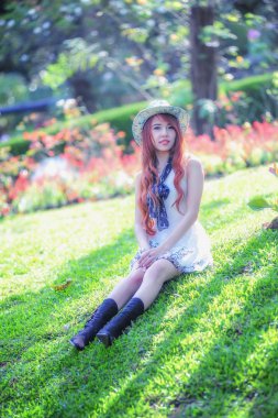 Asya genç kadın bahçede çimlerin üzerine oturan 