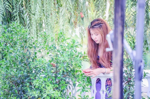 De jonge vrouw Asia in het park en de camera kijken — Stockfoto