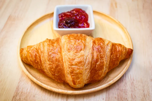 Tasty croissants with jam on wooden background. — Stock Photo, Image