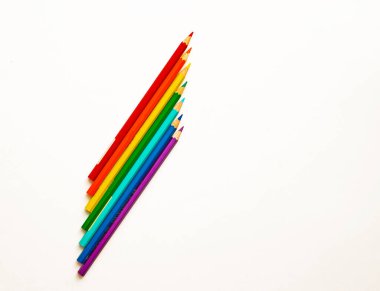 Gökkuşağı renkli kalemler ofis, okul ve illüstrasyon için beyaz arka planda birbirine yakın yatar..
