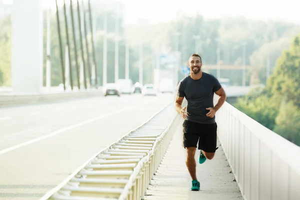 Young man running on the bridge. — Stock Photo, Image