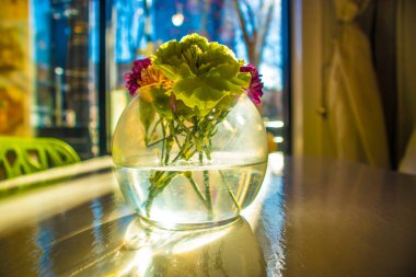 Suda çiçekler ve bulanık bir arka plan sahnesi olan cam bir kavanoz.