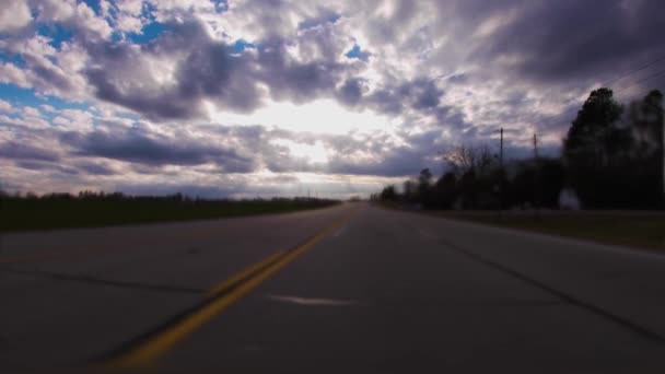 田舎道の下の雲と青空を通して天の太陽が照りつける — ストック動画