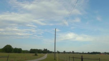 Gürcistan 'ın kırsal kesimindeki ahşap tellerin arkasındaki yeşil çitli ve bulutlu arazili güzel tarım arazileri ve uzak binalar.