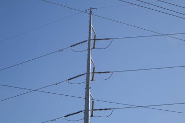 Elektrik hatlarını, direği ve açık mavi gökyüzünü kapatın Güzel bir gün