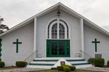 Augusta, Ga USA - 03-17-21: Klasik yeşil ve beyaz sıva kilisesi ve bulutlu gökyüzü