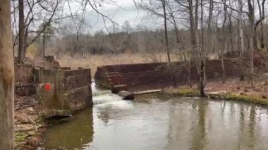 Gürcistan 'da küçük bir şelale ile sonbaharda ormanın içinden akan bir nehrin barajı ve gölgesi. 
