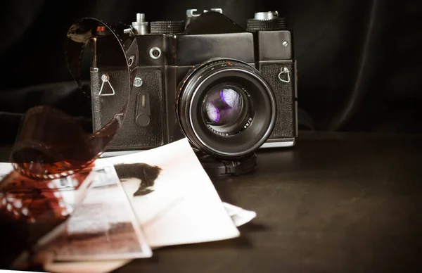 old camera on a black background with film and old photos