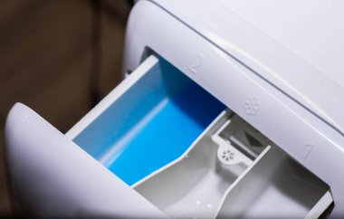 Çamaşır makinesine mavi renkli sıvı çamaşır tozu dökülüyor.