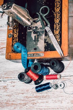 Aksesuar dikme makinesi, renkli iplikler, makas ve mezura.