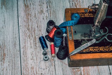 Aksesuar dikme makinesi, renkli iplikler, makas ve mezura.