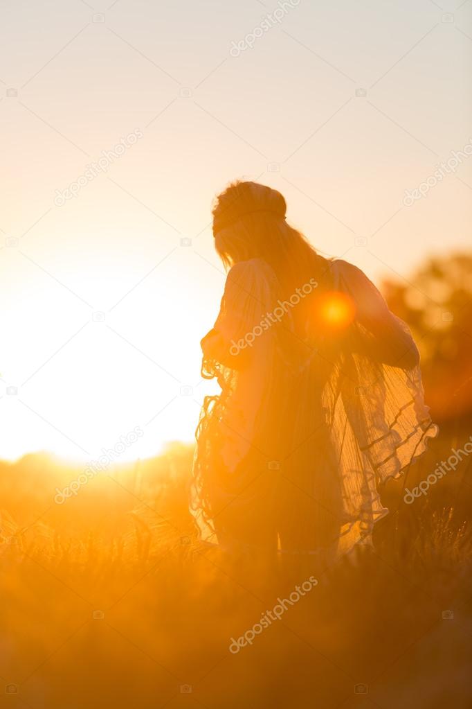 Sexy young Girl at sunset in fields with translucent cloths.