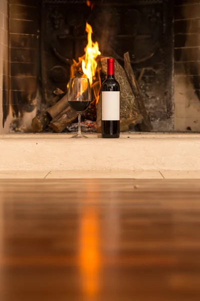 Wine glass and wine beside fireplace. — Stock Photo, Image