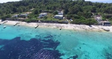 Kıyı üzerinde banliyö evleri ile turkuaz sahil havadan drone sahne.