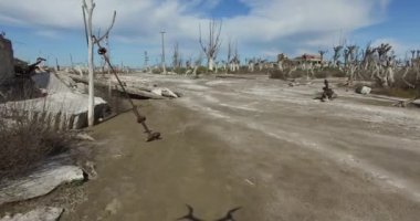 Uçağı tahrip terk edilmiş şehir sahnesinde. Gri kirli sokak. Epecuen Arjantin. Yavaş uçan kamera yere yakın.