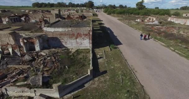 Légi drone jelenet az elhagyott, elpusztult város. Lebontották, régi, rubbled házak. Kamera regisztrálja szomszédságában, lassan mozog oldalirányban. A magányos utcán sétáló emberek. Szomorú, utca-és városrészlet. — Stock videók
