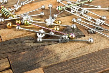 Ahşap arka plan üzerinde piercing için takı.