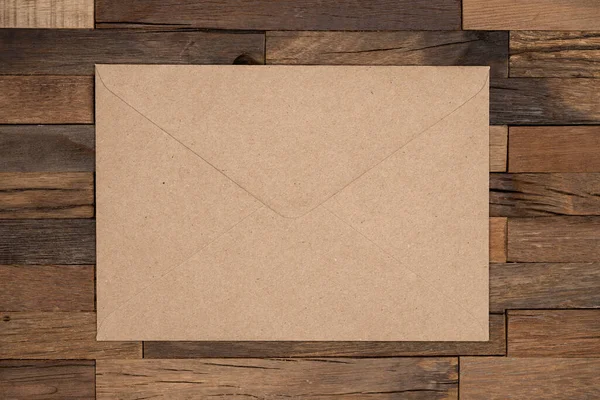 Brown craft envelope on wooden background. Mail envelope or letter.