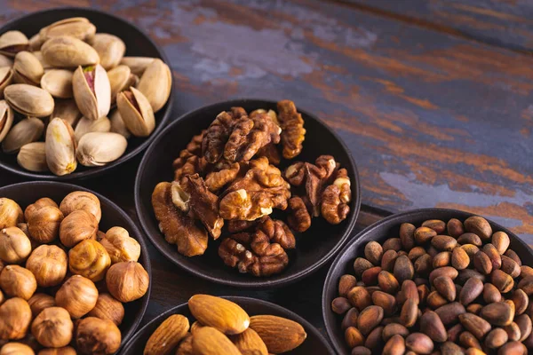 Variety of nuts in bowl on wooden background. Top view. Mixed nuts in ceramic bowl.