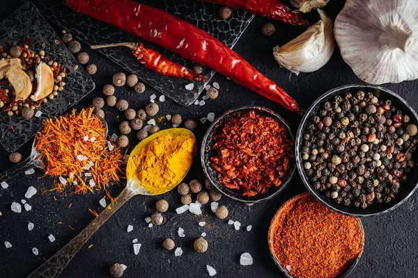 Baharat ve yemek için. Koyu arkaplanda kaşıklarda ve kaselerde çeşitli baharatlar. 