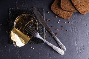 Arka planda metal bir kavanoza balık serpiştiriyor. Yağda tütsülenmiş balık konservesi.