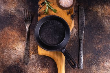 Tahta kesme tahtasına saplı boş siyah yuvarlak demir tava. Aşçılık arka plan kavramı. 