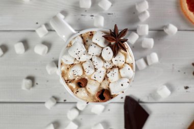 Çikolata, anason, tarçın ve beyaz ahşap masaya bir dilim kurutulmuş greyfurt serpiştirilmiş bir fincan sıcak kahve. Üst görünüm.