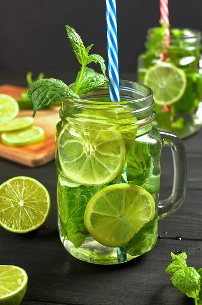 İki bardak limonata ya da taze limon ve naneli mojito kokteyli. Siyah masada soğuk, ferahlatıcı bir kokteyl.