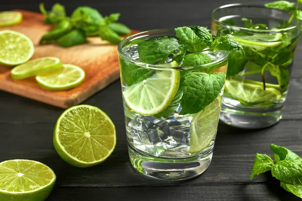 İki bardak limonata ya da buzlu mojito kokteyli, taze nane ve limon. Siyah masada soğuk, ferahlatıcı bir kokteyl.
