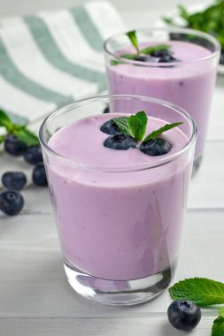 Taze yaban mersini ve nane yapraklarıyla servis edilen iki bardak yabanmersinli yoğurt..