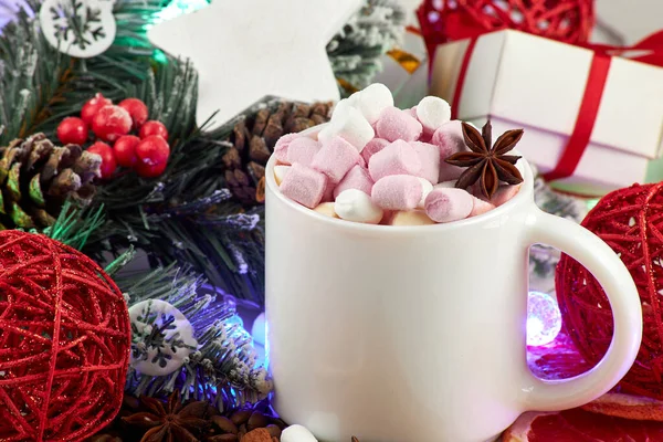 Winter hot drink, gift boxes, Christmas decorations and garland. Mug of hot coffee with marshmallows, anise, cinnamon and a slice of dried grapefruit. Christmas and New Year concept.