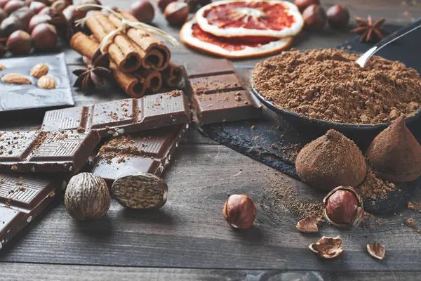 Farklı türde çikolata, kakao tozu, fındık ve diğer baharatlar. Ev yapımı trüf mantarı yapmak için gerekli malzemeler.